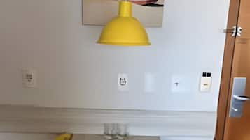 A small dining area with a wooden table, a yellow pendant light, and a painting of a boat on the wall.
