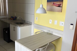 Una cocina con encimera de granito, un lavamanos, una silla blanca, una mesa y una lámpara colgante.