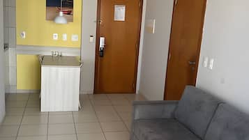 A room with a kitchenette, a sofa, and a door.