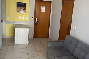 Una habitación con kitchenette, un sofá y una puerta.
