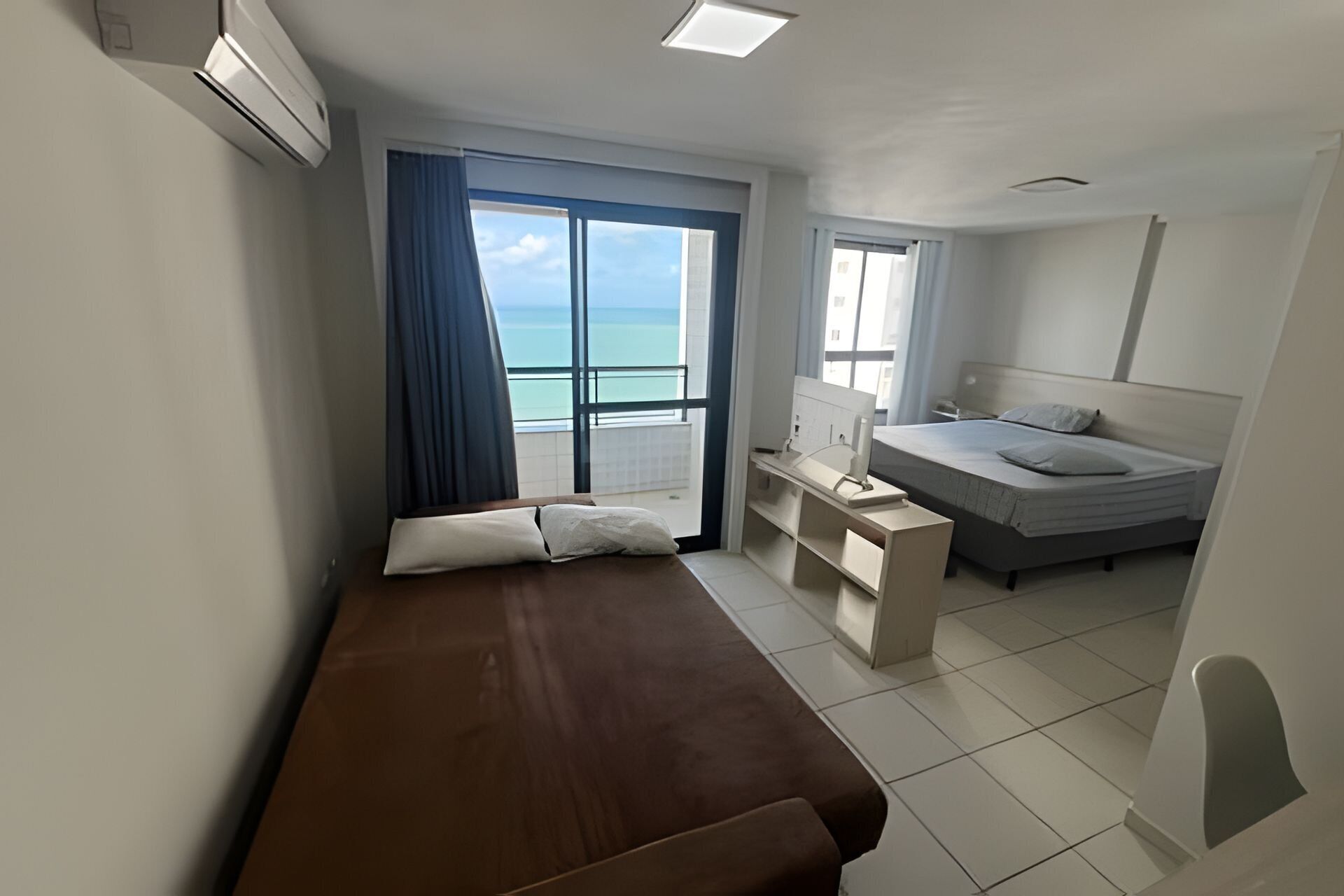 Un dormitorio con cama, escritorio y vista al océano.