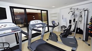 Une salle de sport équipée de machines de cardio, d’appareils de musculation et d’un tapis de course.