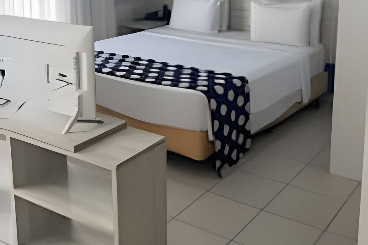 Een hotelkamer met een bed, een bureau en een computer.