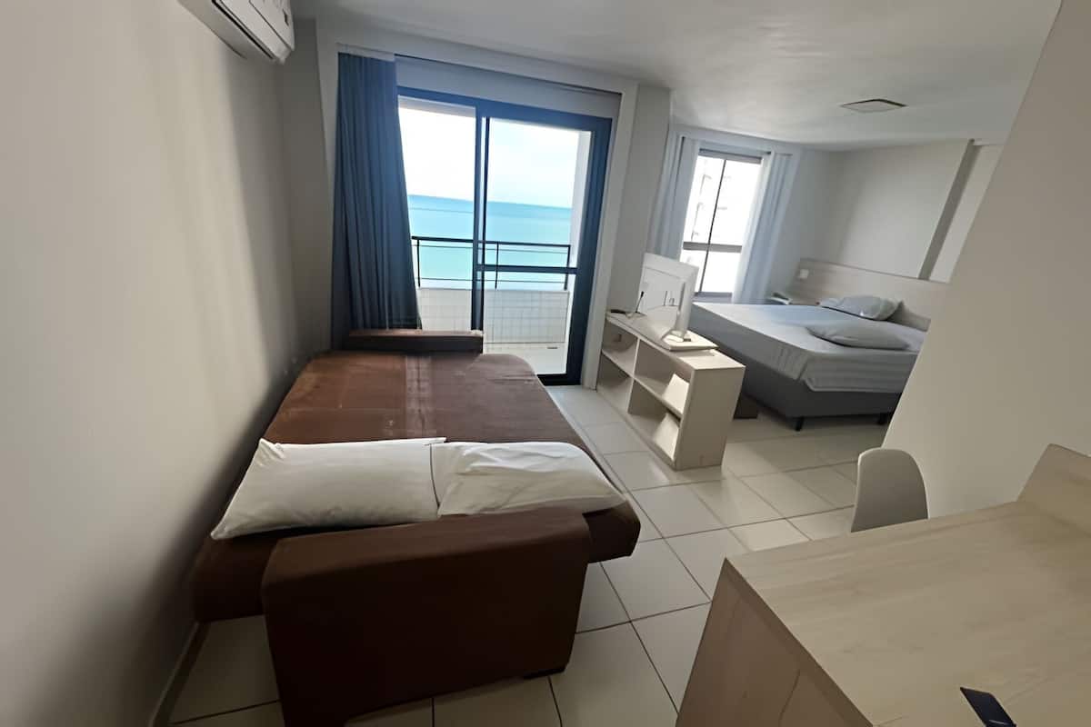 Een kamer met een bed, een bureau en een raam met uitzicht op zee.