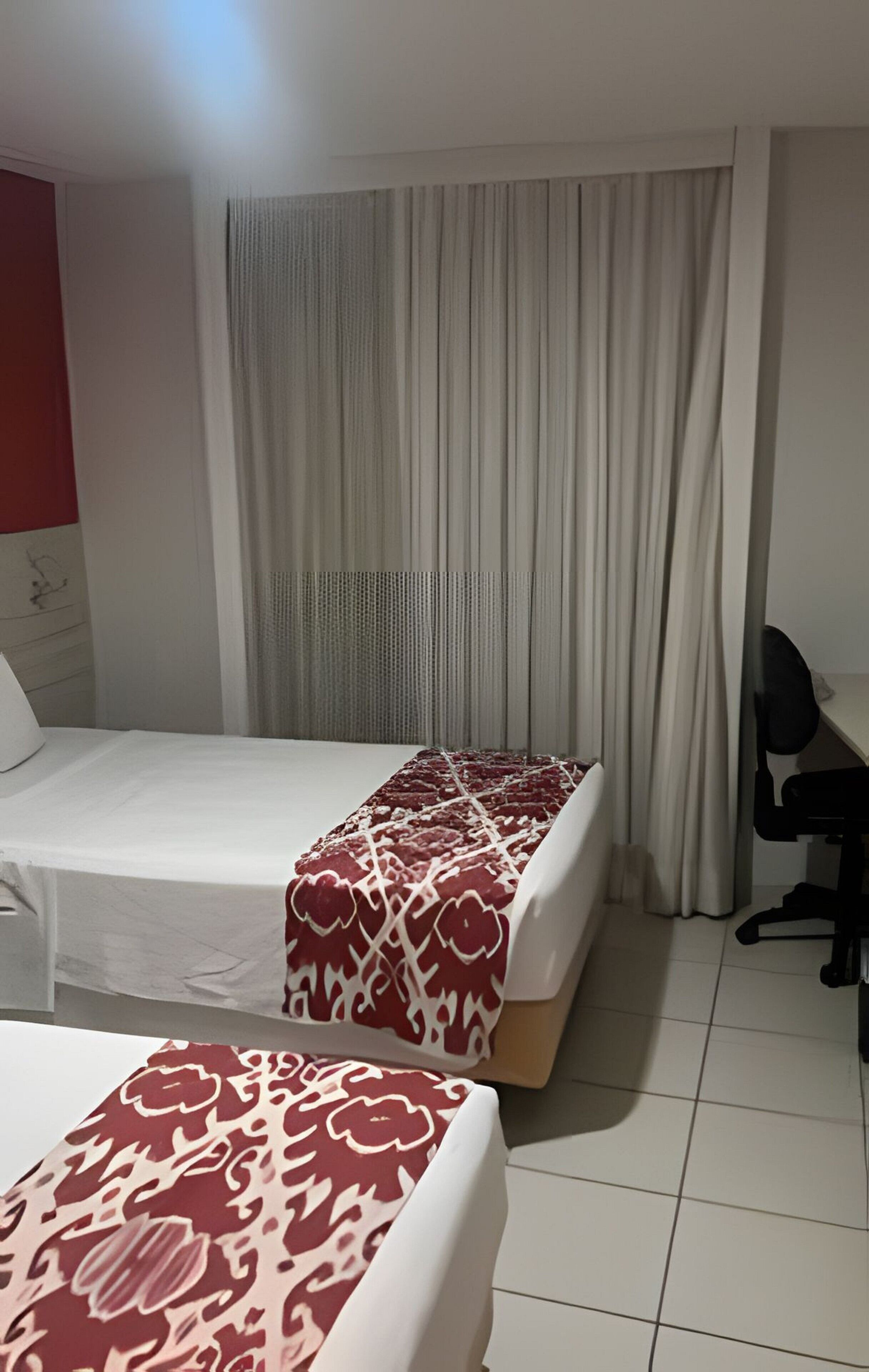 A hotel room with two beds, a desk, and a chair.