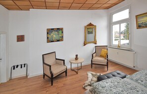 Una habitación con dos sillones, una mesita redonda, un sofá y una ventana con vistas.