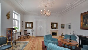 Um quarto amplo com lustre, lareira e um espelho grande.