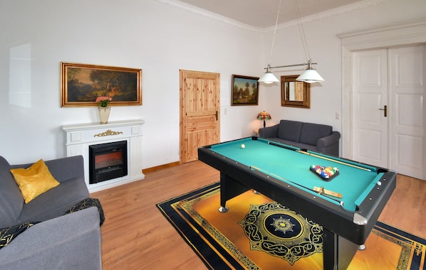 Una sala de estar con mesa de billar, chimenea, sofá y una puerta.