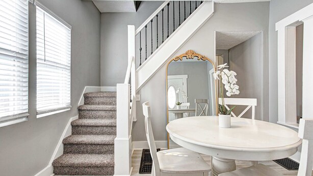 A staircase with white railings and carpeted steps leading to a landing. - The Yellow Door – Cozy Indianapolis Retreat (Indianapolis)