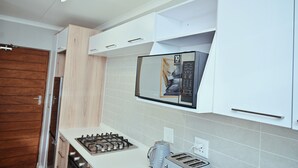 A modern kitchen with white cabinetry, a built-in microwave, a gas stove, and a toaster.