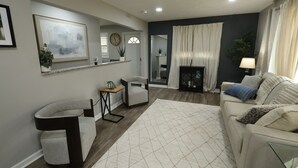 Una sala de estar moderna con sofá, sillón y chimenea.