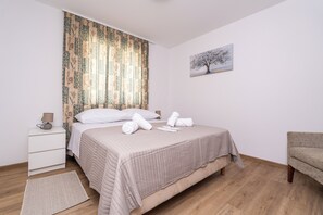 Ein ordentlich eingerichtetes Schlafzimmer mit Bett, Nachttisch und Stuhl.