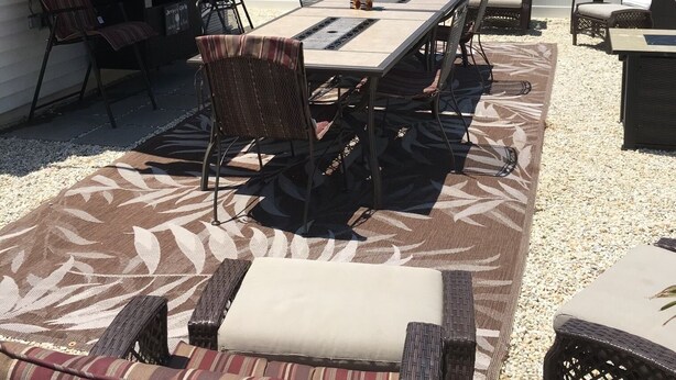 Een terras buiten met een eettafel, stoelen en een barbecuehoek.