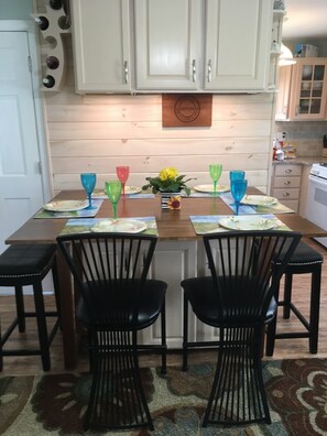A dining area with a wooden table, black chairs, and colorful glassware. - Perfect 2-bedroom plus sleeping porch house with AC in peaceful sleeps 6 (Lavallette)