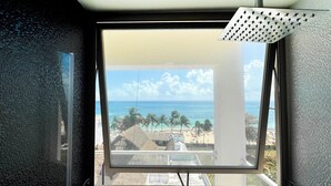A window with a view of a beach, palm trees, and a clear sky. - Grand Boréna Hotel Boutique (Playa del Carmen)