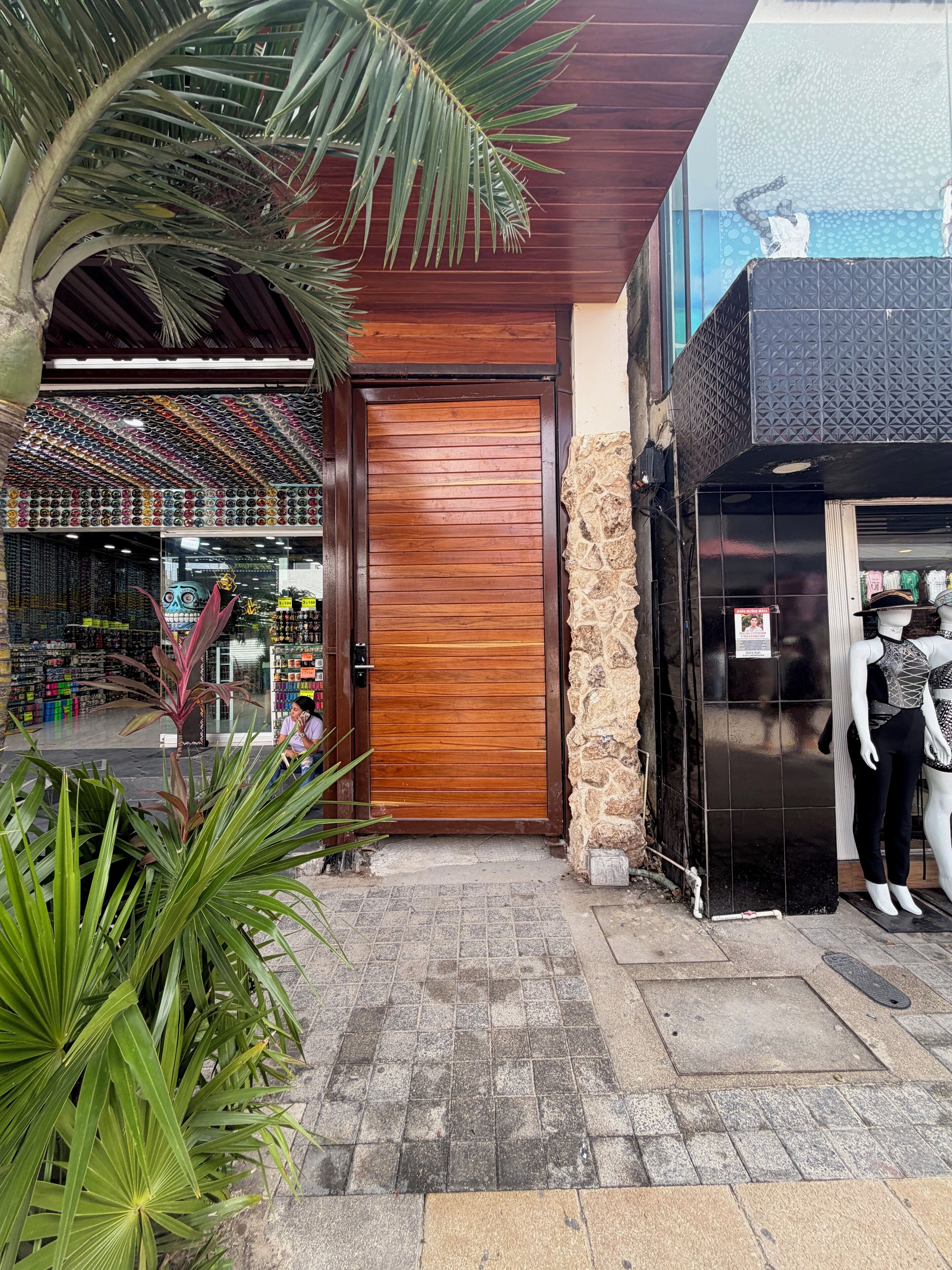 A storefront with a wooden door, a mannequin, and a variety of products on display.