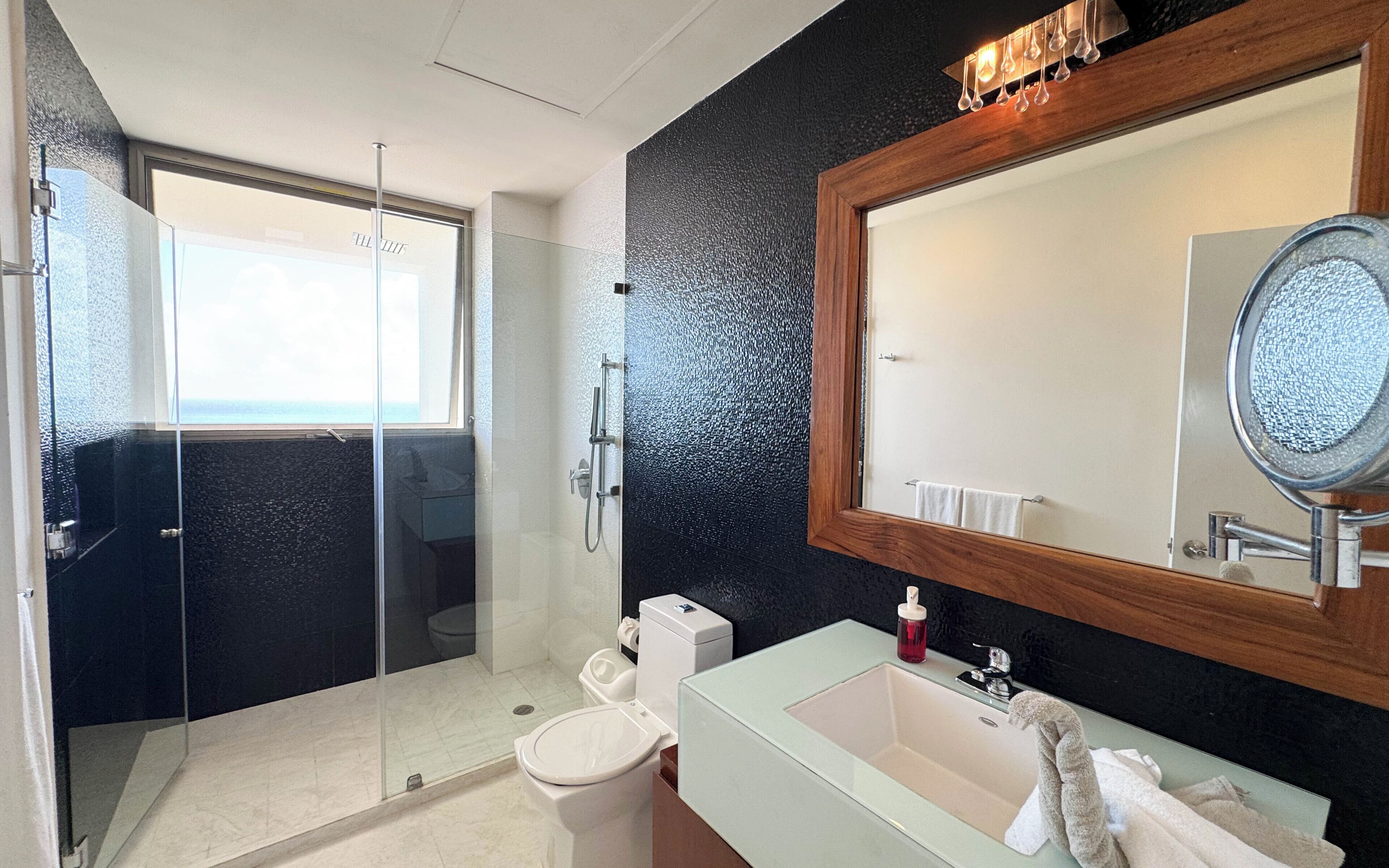 Un bagno moderno con cabina doccia in vetro, un water, un lavandino con specchio e un porta asciugamani.