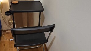 Een zwarte stoel met een metalen frame en een zwarte tafel met een houten dienblad.