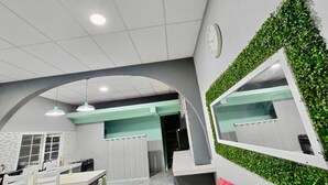 Ein modernes Interieur mit Essbereich, einer Rezeption und einer grünen Wand mit einer Uhr.
