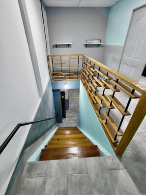 A staircase with wooden handrails and a metal banister, leading to a landing with a light fixture.