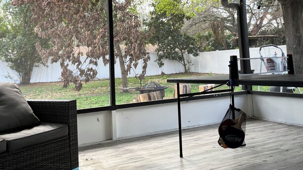 A covered patio area with a view of a backyard, a wicker sofa, and a hanging fan. - Cozy RV Camper in tranquil Brandon near everything (Brandon)