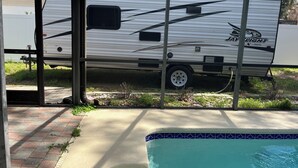 A recreational vehicle (RV) parked near a swimming pool with a covered patio area. - Cozy RV Camper in tranquil Brandon near everything (Brandon)