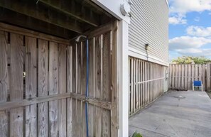 Une porte de garage en bois, une terrasse en béton et une clôture en bois.