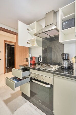 Eine moderne Küche mit weißen Schränken, einem eingebauten Backofen und einer Kaffeemaschine.
