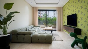 Ein modernes Wohnzimmer mit einem Ecksofa, einem Flachbildfernseher und einer Topfpflanze.