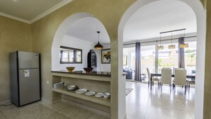 Une cuisine moderne dotée d’un réfrigérateur encastré, d’un plan de travail avec des bols, et d’un coin repas comprenant des chaises et une table.