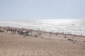 Una playa con gente, sombrillas y un caballo.