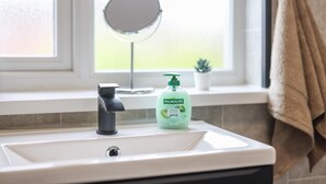 A bathroom sink with a mirror above it, a green bottle of Palmolive soap, and a towel hanging on the wall. - Contractor Stay - WI-Fi - Pet Friendly - Parking (Consett)