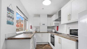 A modern kitchen with white cabinets, a wooden countertop, and a herringbone floor pattern. - Contractor Stay - WI-Fi - Pet Friendly - Parking (Consett)
