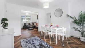 A modern living room with a white dining table set for four, a grey sofa, and a large potted plant. - Contractor Stay - WI-Fi - Pet Friendly - Parking (Consett)