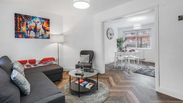 A modern living room with a sofa, armchair, coffee table, and a painting of deer. - Contractor Stay - WI-Fi - Pet Friendly - Parking (Consett)