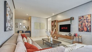 A modern living room with a large flat-screen TV, a sofa, a coffee table, and artwork on the walls. - Luxury 3-Bedroom Getaway in Bouskoura`s Finest (Bouskoura)
