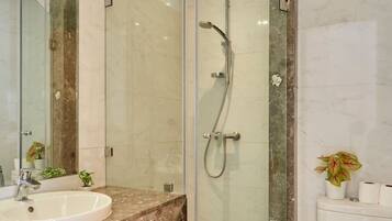 Un baño moderno con ducha envuelta en vidrio, lavamanos de mármol y un inodoro.