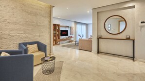A modern living room with a stone accent wall, a round mirror, and a flat-screen TV. - Luxury 3-Bedroom Getaway in Bouskoura`s Finest (Bouskoura)