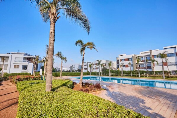 A modern resort with a swimming pool, palm trees, and contemporary buildings.