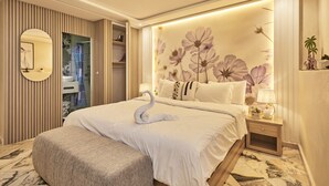 Habitación de hotel con una cama grande, un espejo redondo, una tocador con espejo y un mural floral en la pared.