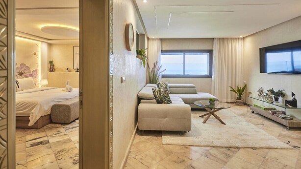 Una sala de estar moderna con un sofá, una mesa de centro de vidrio y un televisor montado en la pared.