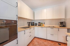 A modern kitchen with white cabinets, a stainless steel oven, and a tiled backsplash. - Modern semi-detached house on the lake with terrace & lake view (Korswandt)