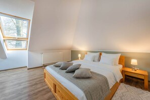 A bedroom with a bed, bedside tables, a window, and a radiator. - Modern semi-detached house on the lake with terrace & lake view (Korswandt)
