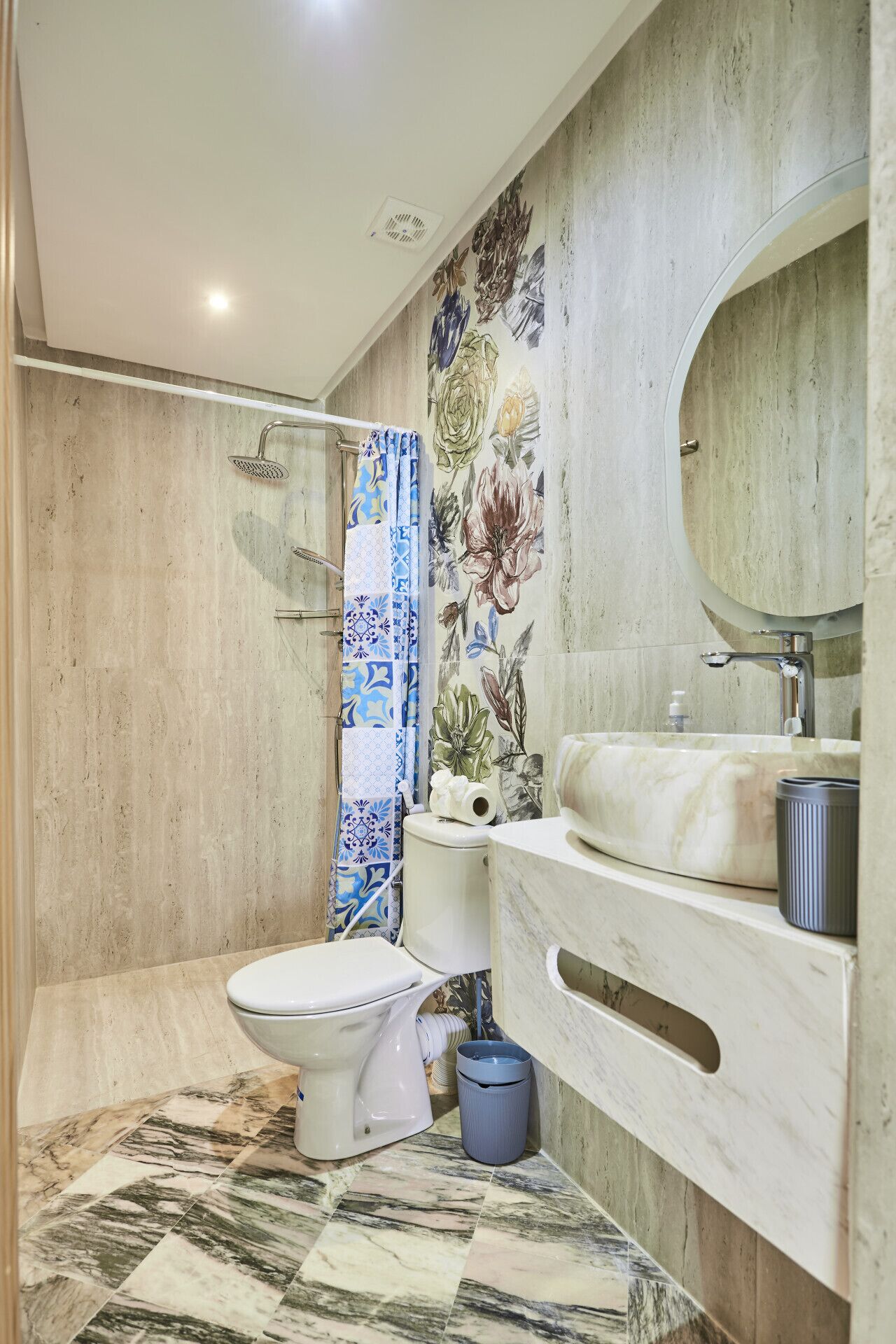 A bathroom with a toilet, shower, sink, and a decorative shower curtain.