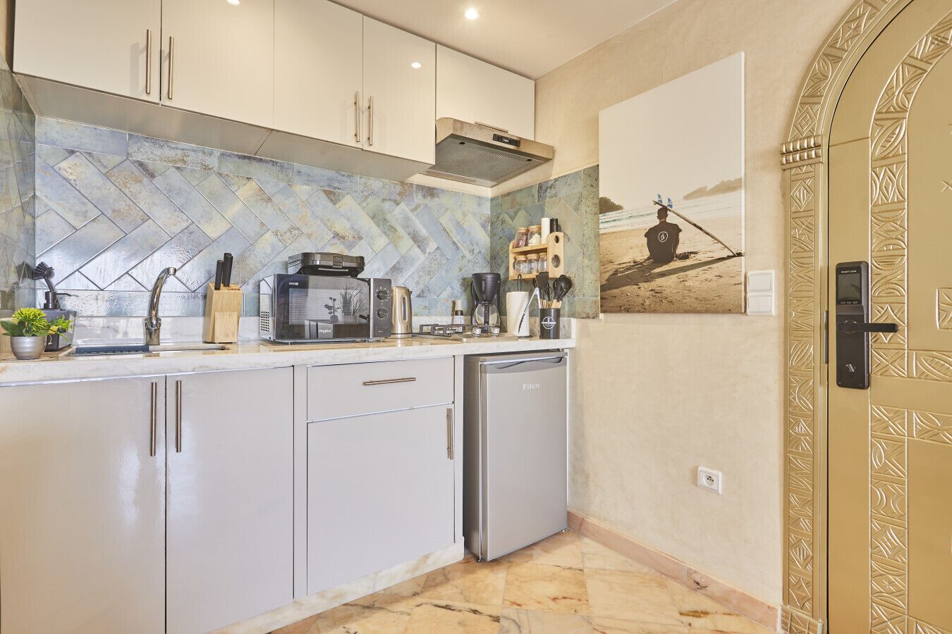 Una cocina moderna con gabinetes blancos, microondas, cafetera y lavavajillas.