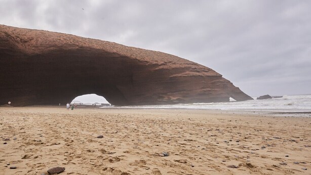 A beach with a large rock arch formation.