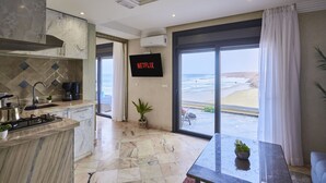 Cocina moderna con una isla grande, un televisor de pantalla plana y vistas a la playa.