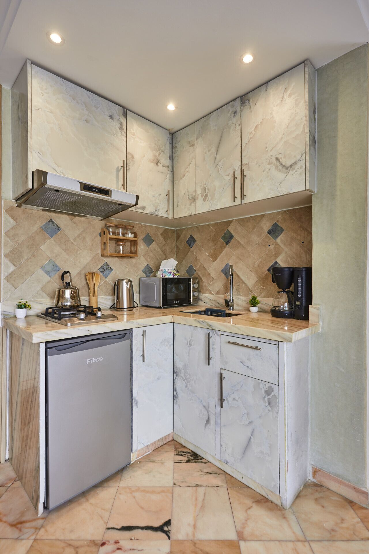 A kitchen with a dishwasher, microwave, kettle, and coffee maker on the counter.