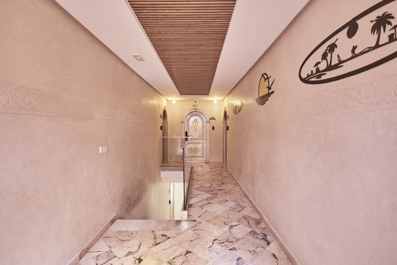 A marble-floored hallway with a wooden ceiling and decorative wall art.