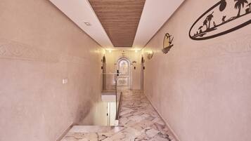 A marble-floored hallway with a wooden ceiling and decorative wall art.